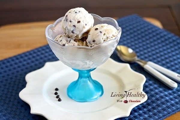 glass serving bowl filled with three scoops of chocolate chop cookie dough ice cream on white place with blue placemat