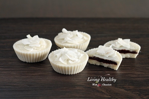 dark table with four coconut dream cups topped with coconut shavings with one cup cut in half showing middle layer