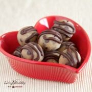 red heart shaped bowl with paleo gluten free cookie dough bite topped with stripes of chocolate