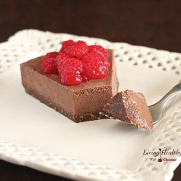 single slice of raspberry chocolate truffle pie topped with fresh raspberries on a white square plate with dark background