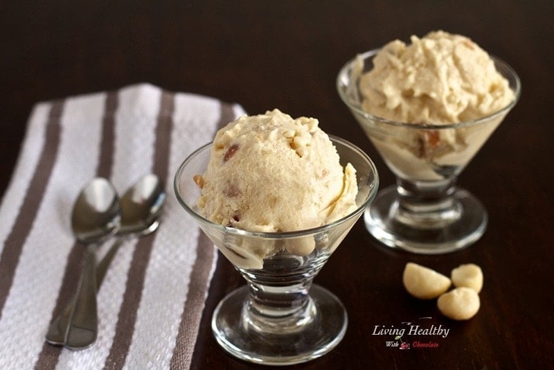 two small glass dishes with honey roasted macadamia nut ice cream with stripped napkin on left with two spoons