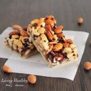 two paleo honey nut bars on parchment paper with a few loose nuts around the bars