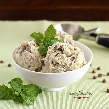 bowl of paleo mint chocolate chip ice cream topped with fresh mint and ice cream scoop in background