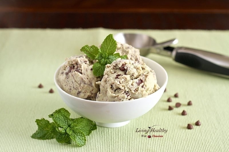 bowl of paleo mint chocolate chip ice cream topped with fresh mint and ice cream scoop in background 