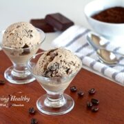 two small glass dishes with coffee chocolate chip ice cream with coffee grinds and chocolate bar in background