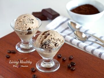 two small glass dishes with coffee chocolate chip ice cream with coffee grinds and chocolate bar in background
