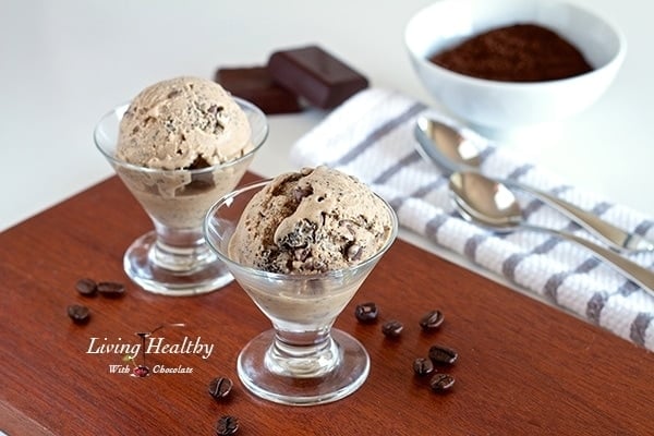 two small glass dishes with coffee chocolate chip ice cream with coffee grinds and chocolate bar in background 