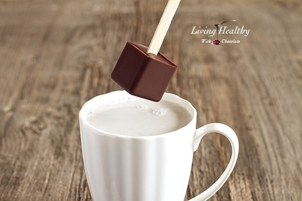 close up of paleo hot chocolate on a popsicle stick being dipped into a cup of milk