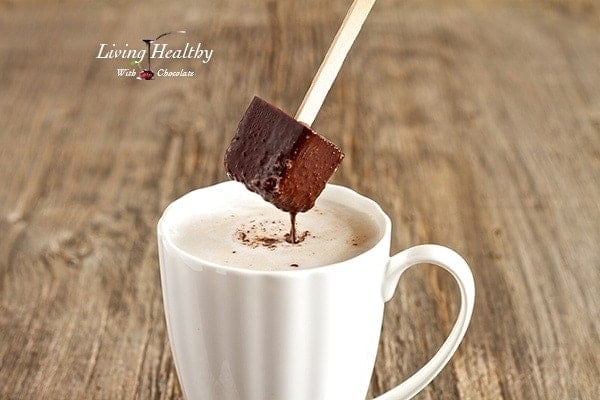 close up of paleo hot chocolate on a popsicle stick being dipped into a cup of milk