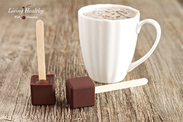 close up of paleo hot chocolate on a popsicle stick with glass of milk in background 