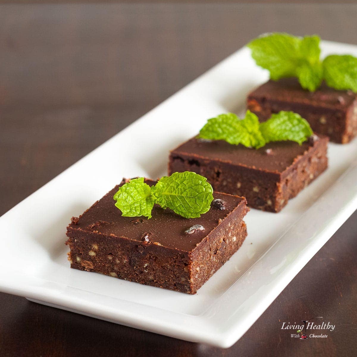 three no bake mint dark chocolate brownie squares topped with fresh mint
