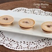 three paleo inside out almond butter cups on a white rectangular with white lace placemat underneath