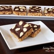 white plate with two square pieces of almond macaroon bar with four more bars in background on long plate