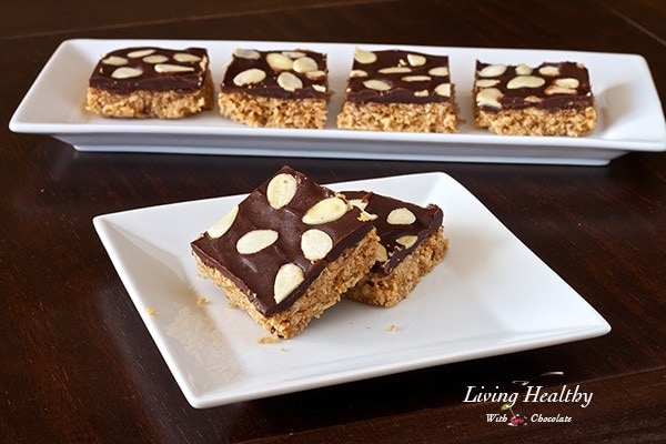 white plate with two square pieces of almond macaroon bar with four more bars in background on long plate