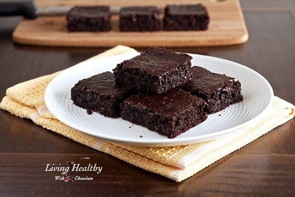 plate sitting on yellow napkin with a stack of flourless chocolate brownies and more brownies on cutting board in background 