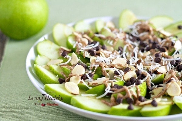 close up of a plate of apple nachos for dessert topped with chocolate and shredded coconut and sliced almonds