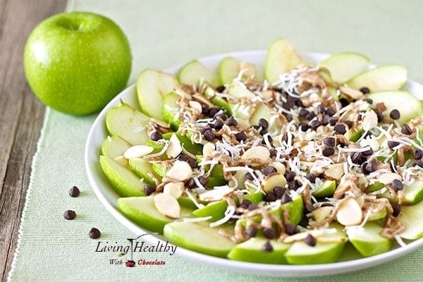 close up of a plate of apple nachos for dessert topped with chocolate and shredded coconut and sliced almonds