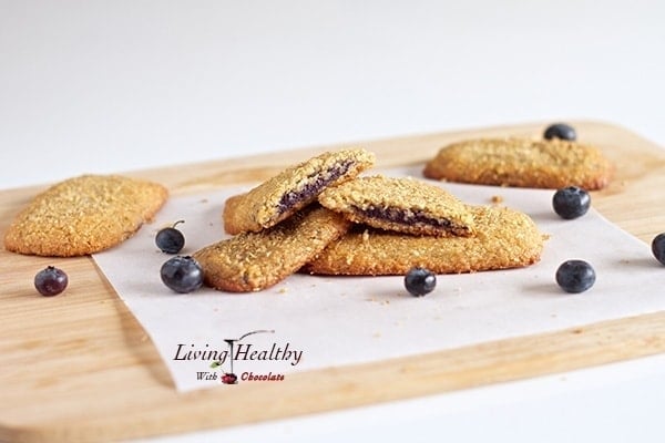 homemade blueberry nutrigrain bars on wooden cutting board with parchment paper and a few loose blueberries