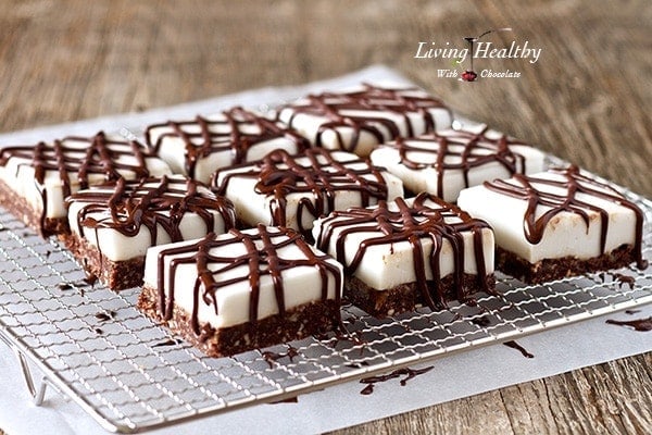 several square pieces of chocolate haupia dessert bars cooling on a wire rack on a wooden table