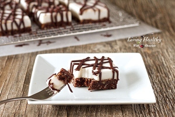 white plate in foreground with one slice of chocolate haupia dessert bar with fork and more squares in background cooling