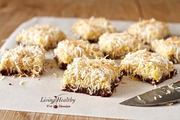 parchment paper on wooden table with numerous square of pineapple coconut dessert bars