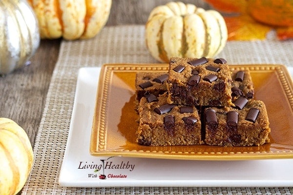 plate stacked with fudgy pumpkin blondes with small pumpkins in background as decoration 