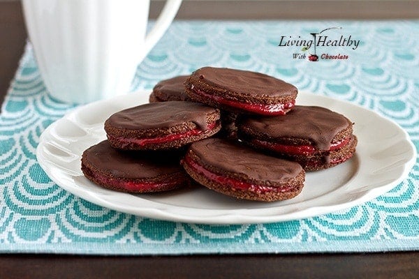 plate of chocolate strawberry jam cookies on aqua colored placemat with white mug in background 