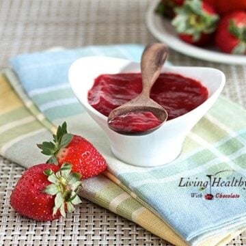 serving dished filled with homemade sugar free strawberry jam with wooden spoon on top and strawberries on side and behind
