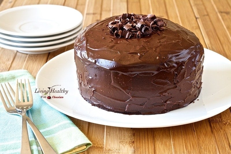 large chocolate cake topped with chocolate shavings in the middle on a white serving dish