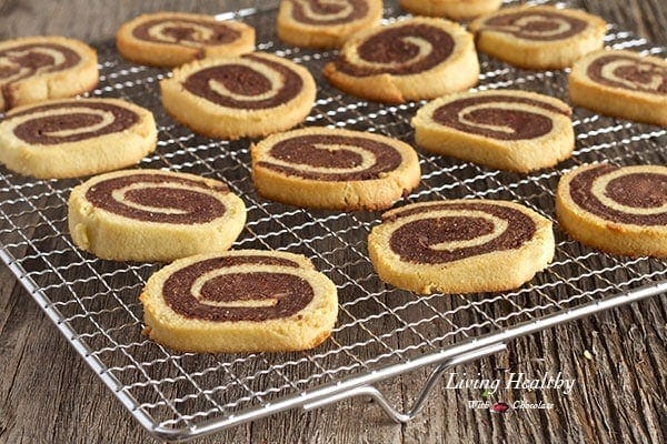 wooden table with a wire rack with rows of paleo pinwheel cookies cooling 