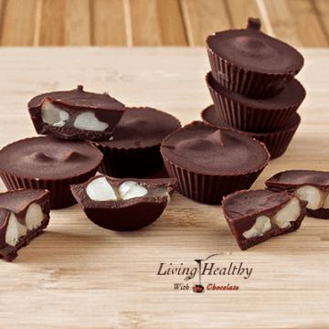 wooden table topped with several chocolate caramel macadamia nut cups with several cut in half