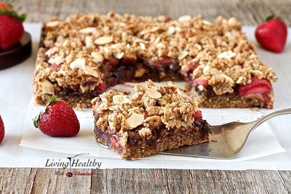 close up of a square piece of a paleo chocolate strawberry crumble bar with larger portion in background
