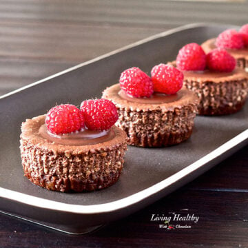 plate of four mini chocolate cheesecakes topped with raspberries