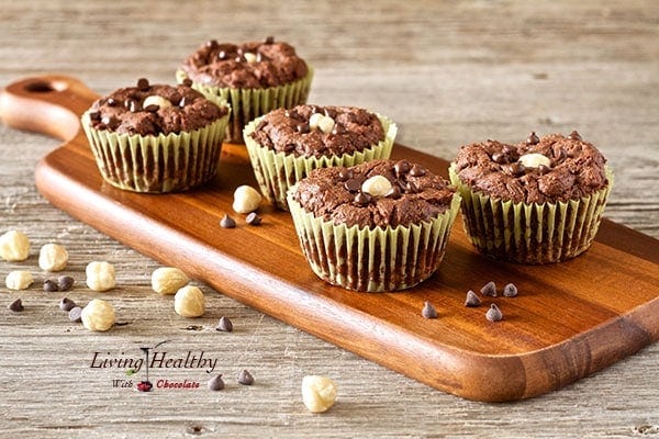 five chocolate hazelnut nutella muffins on cutting board with loose nuts sprinkled on and around cutting board