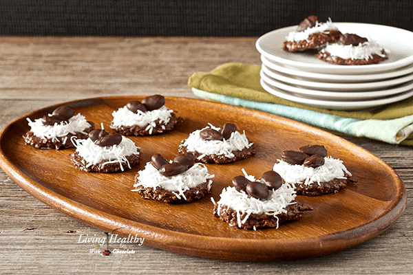 wooden serving tray with six cookies topped with coconut and a stack of plates with more cookies in background 