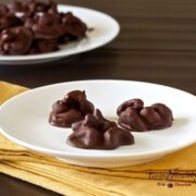 paleo honey roasted cashew chocolate drops on a white plate on dark table with yellow napkin