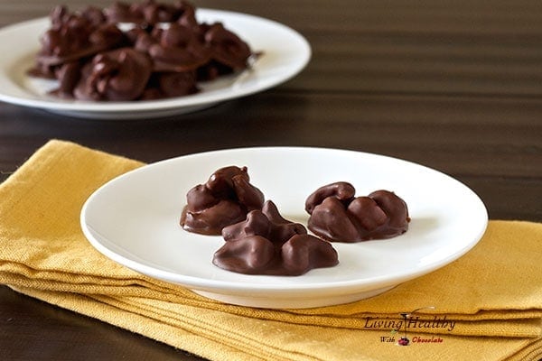 paleo honey roasted cashew chocolate drops on a white plate on dark table with yellow napkin