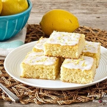 plate of five lemon coconut glazed brownie bars with bowl of lemons in background