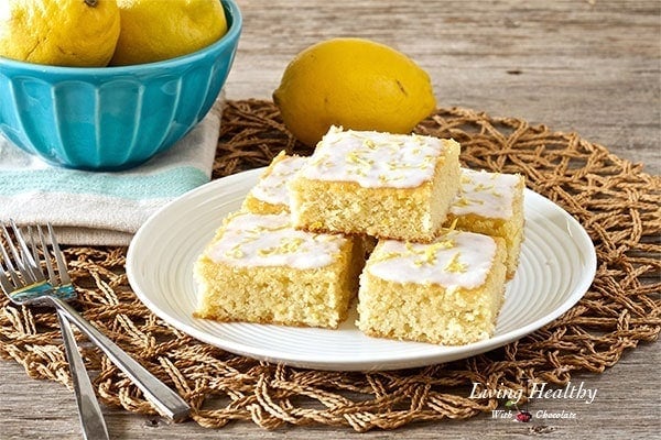 plate of five lemon coconut glazed brownie bars with bowl of lemons in background 