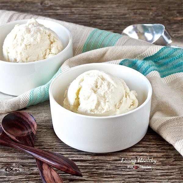 two small white serving bowls with paleo lychee ice cream and wooden spoons to the left 