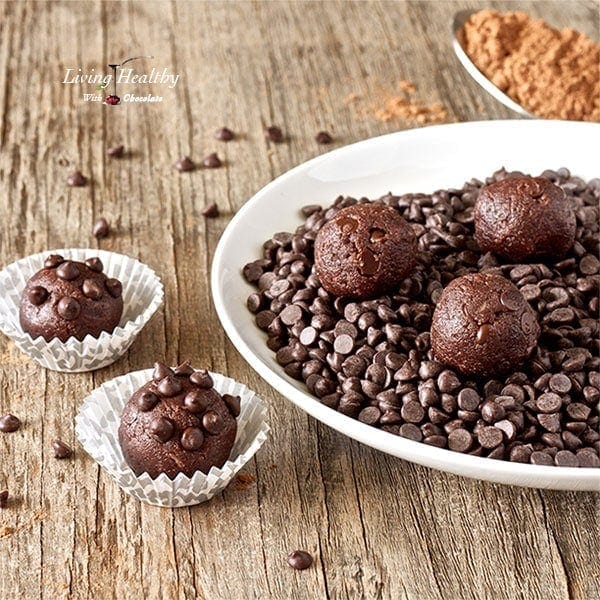 plate of no bake double chocolate chip cookie dough balls with two more balls in paper cups to the left