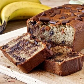 loaf of peanut butter cup banana bread with two slices cut and bananas in background