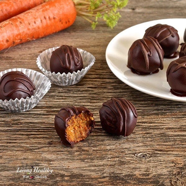 table and white plate with carrot cake truffles and two carrots in the background