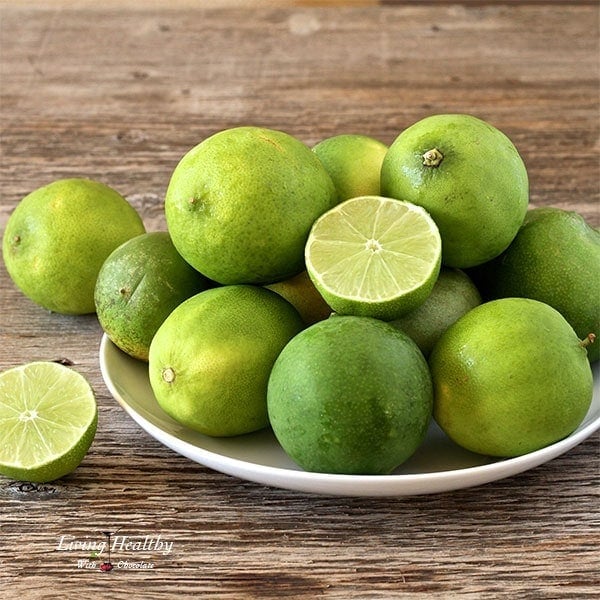 wooden table with a plate filled with limes to be used for paleo key lime pie