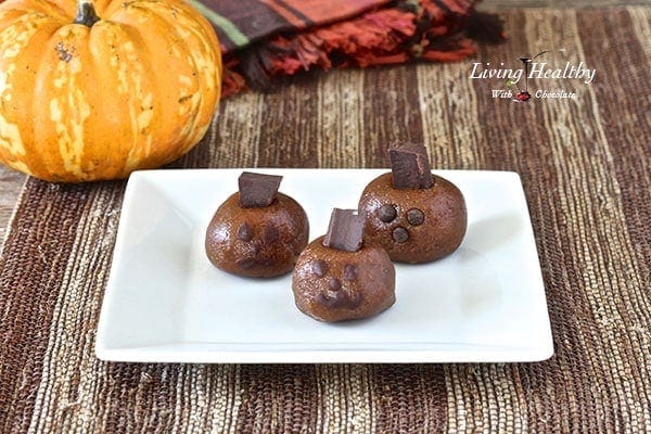 Halloween almond butter pumpkin truffle heads on a white plate with colorful napkins and pumpkin in background 