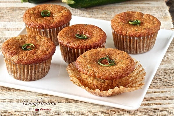 five zucchini muffins on a white plate  