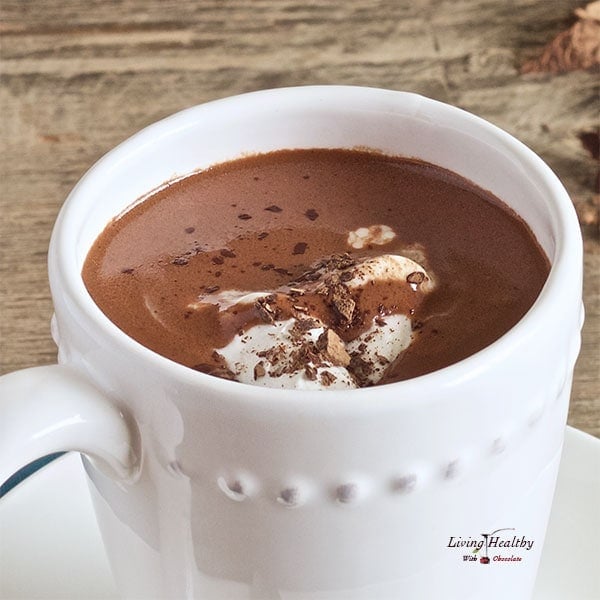 close up of a cup of hot chocolate served in white mug with small dish with chocolate shavings on top