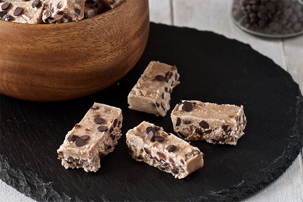 Coconut Candy Bars on a black plate and a wooden bowl