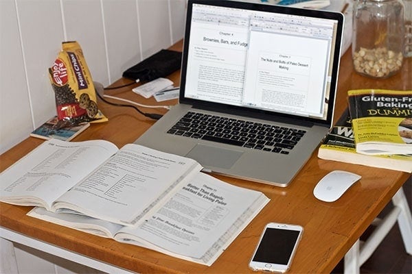 A desk with a laptop computer sitting on top of a wooden table