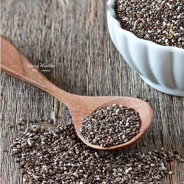 spoon and pile of loose chia seeds sitting next to a bowl filled with chia seeds 